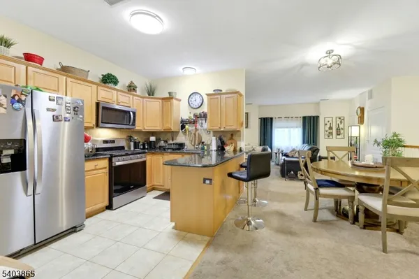a kitchen with stainless steel appliances kitchen island granite countertop a refrigerator and microwave