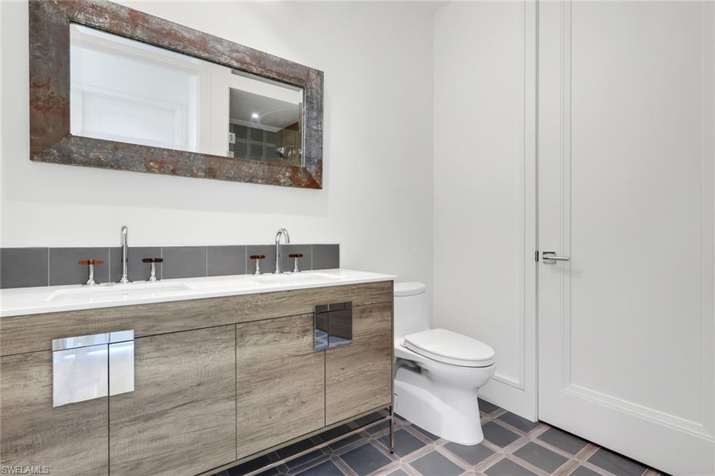 1798 Holiday Lane Naples, FL 34104 - Photo 18 of 31 a bathroom with a sink a toilet and mirror