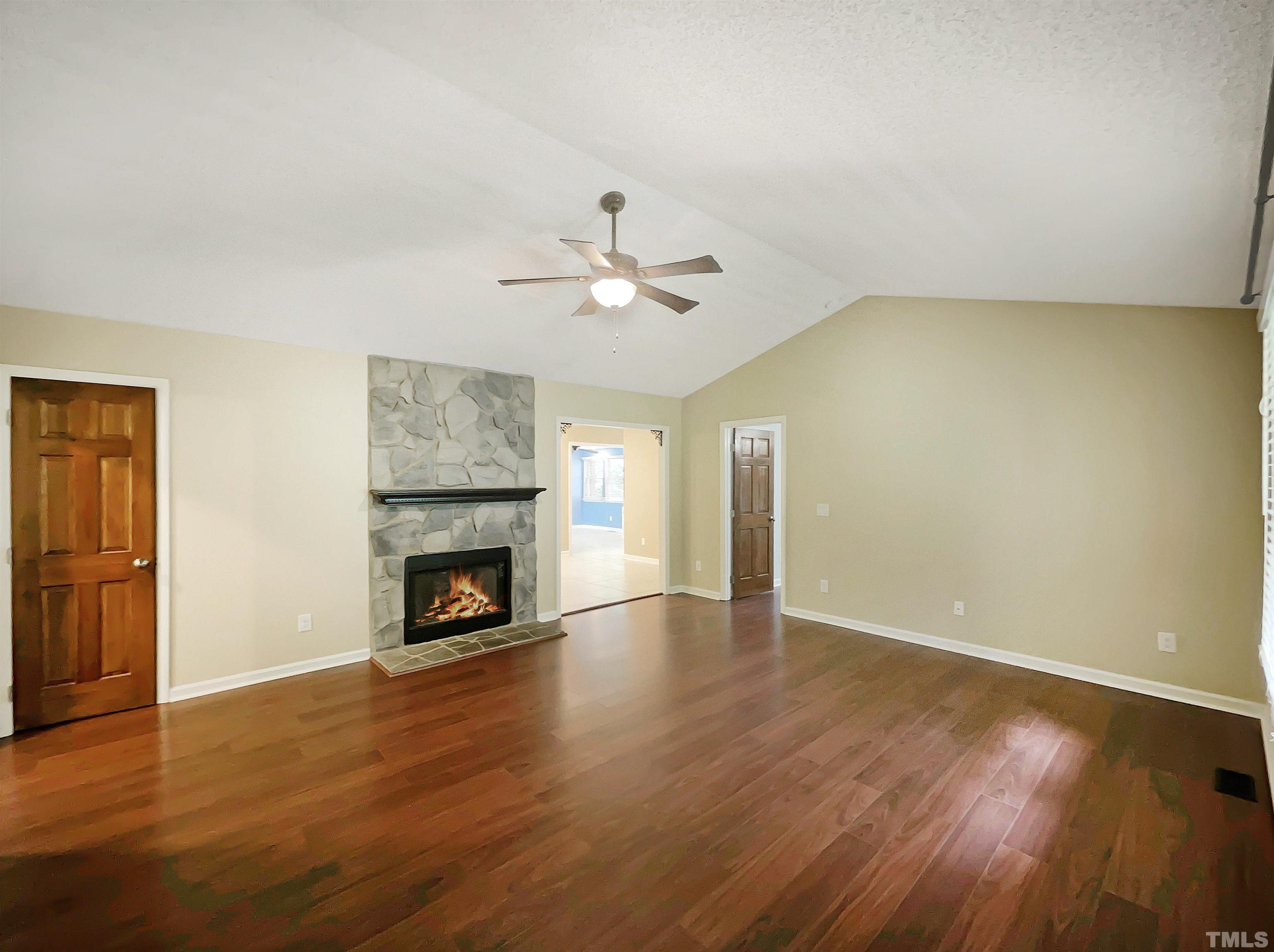 2025 Canterbury Road Clayton, NC 27520 - Photo 12 of 18 an empty room with windows a fireplace and wooden floor