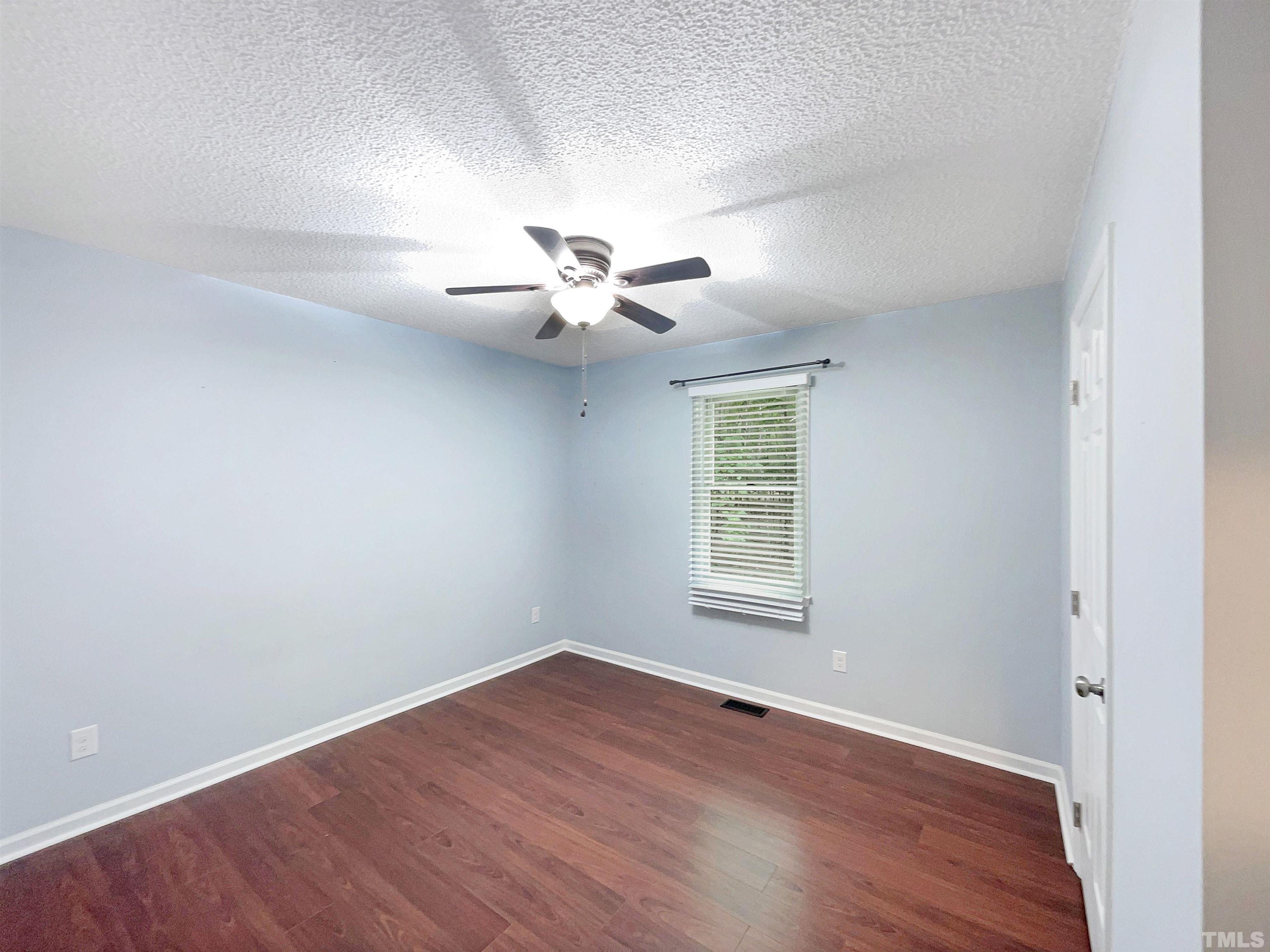 2025 Canterbury Road Clayton, NC 27520 - Photo 13 of 18 an empty room with wooden floor fan and windows
