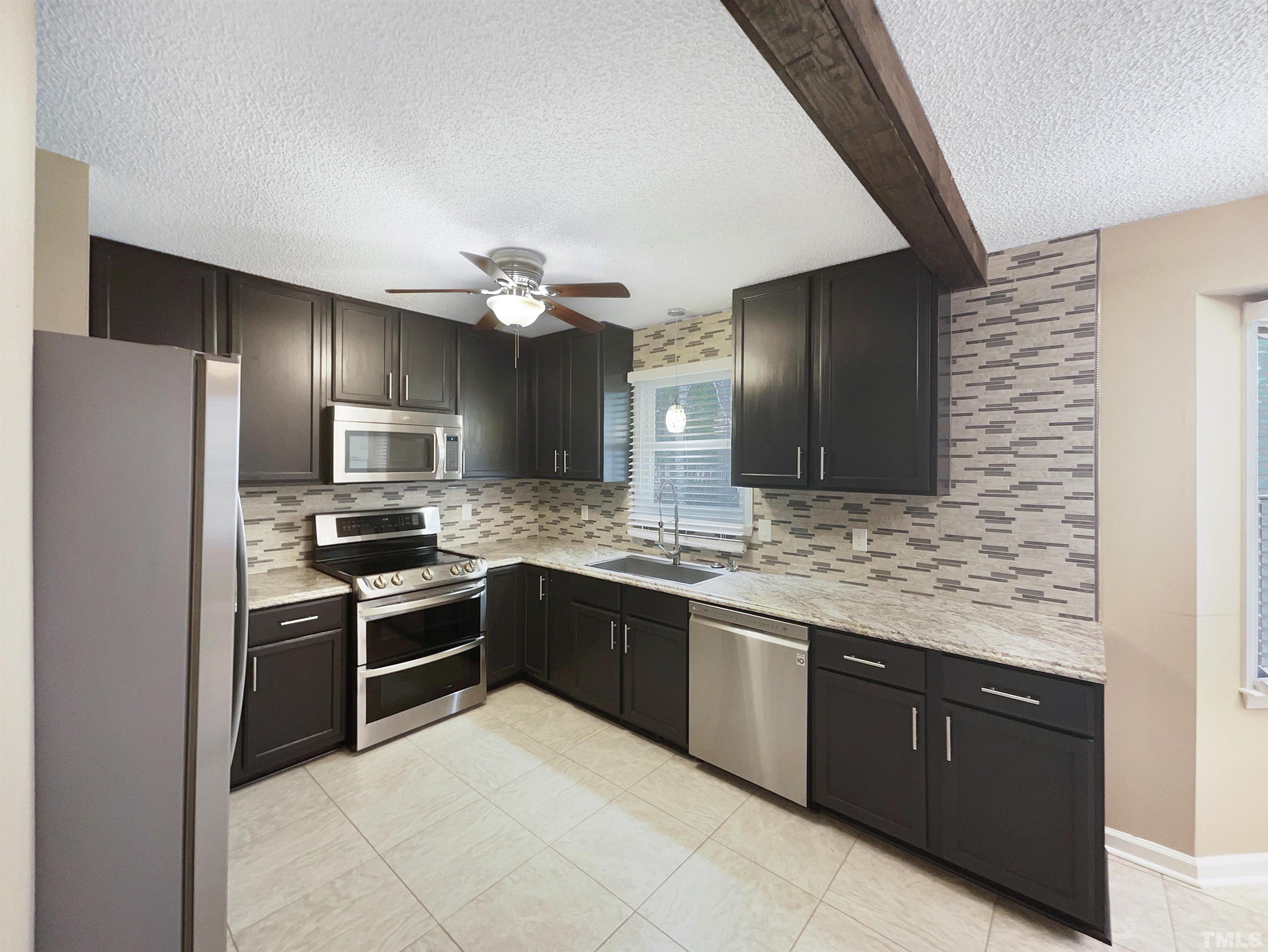 2025 Canterbury Road Clayton, NC 27520 - Photo 15 of 18 a kitchen with stainless steel appliances granite countertop a sink and stove top oven