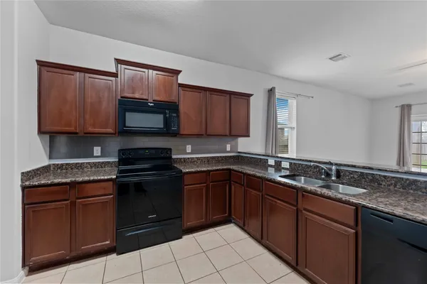 a kitchen with stainless steel appliances granite countertop a stove a sink and a microwave