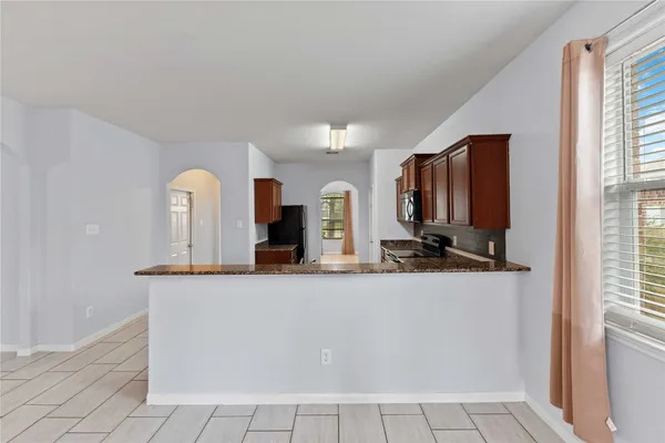 a view of a kitchen with kitchen island a sink wooden floor and a large window