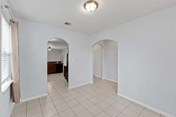 an empty room with chandelier fan and windows