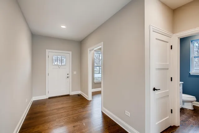 a view of an empty room with wooden floor and a bathroom