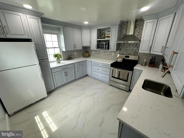 a large white kitchen with cabinets a sink a window and a refrigerator
