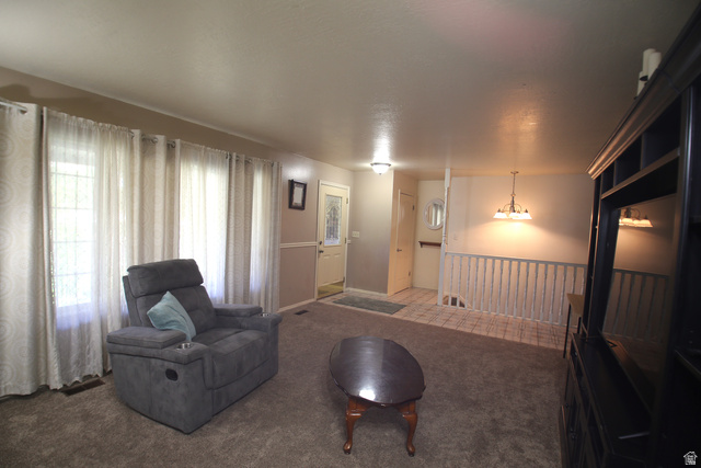 1612 East 450 South Springville, UT 84663 - Photo 11 of 48 Carpeted living area featuring multiple windows, a decorative front entry door with glass inserts, a tiled entryway, and a white baluster railing