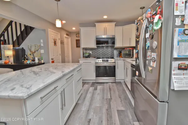 a kitchen with stainless steel appliances granite countertop a refrigerator a oven and a sink with dishwasher