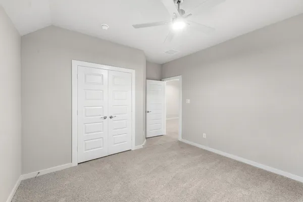 an empty room with closet and a ceiling fan