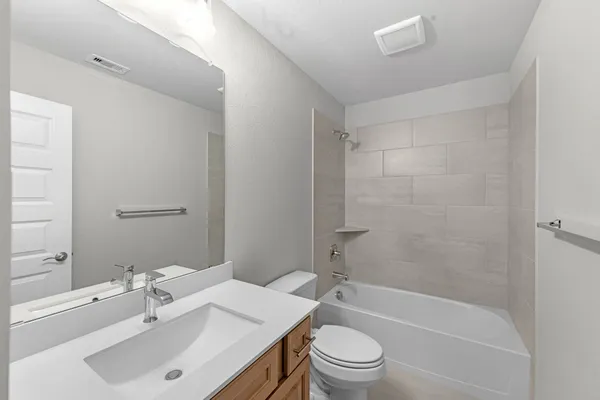 a bathroom with a bathtub shower sink vanity mirror and toilet