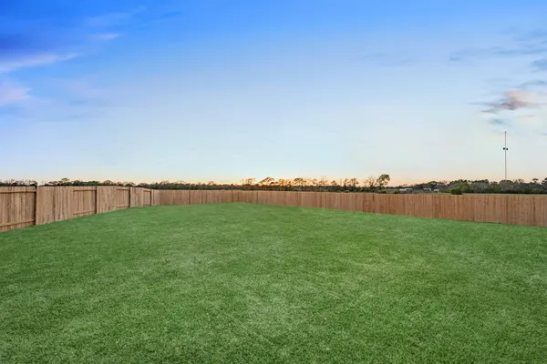 a view of a green field with wooden fence