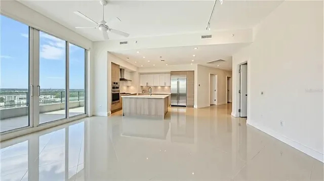 a view of kitchen with kitchen island a large window cabinets a sink and stainless steel appliances