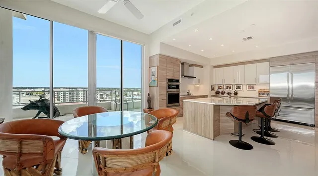 a kitchen with stainless steel appliances kitchen island granite countertop a table chairs sink and cabinets