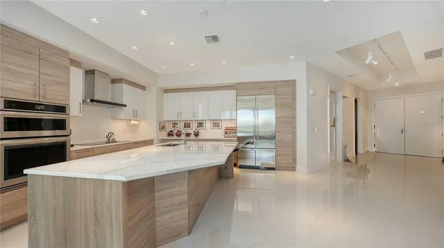 a large kitchen with stainless steel appliances a large counter top a stove and a refrigerator