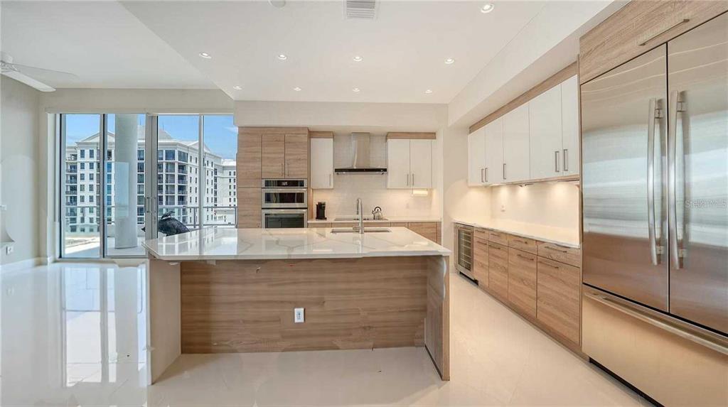 111 South Pineapple Avenue, Unit 1210 Sarasota, FL 34236 - Photo 31 of 54 a kitchen with kitchen island a counter top space a sink stainless steel appliances and cabinets