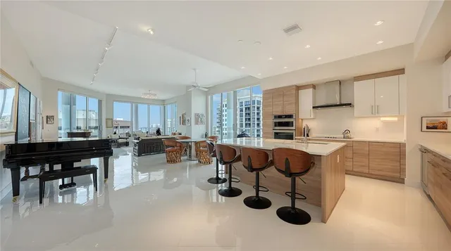 a kitchen with stainless steel appliances granite countertop a stove a sink a dining table and chairs with wooden floor