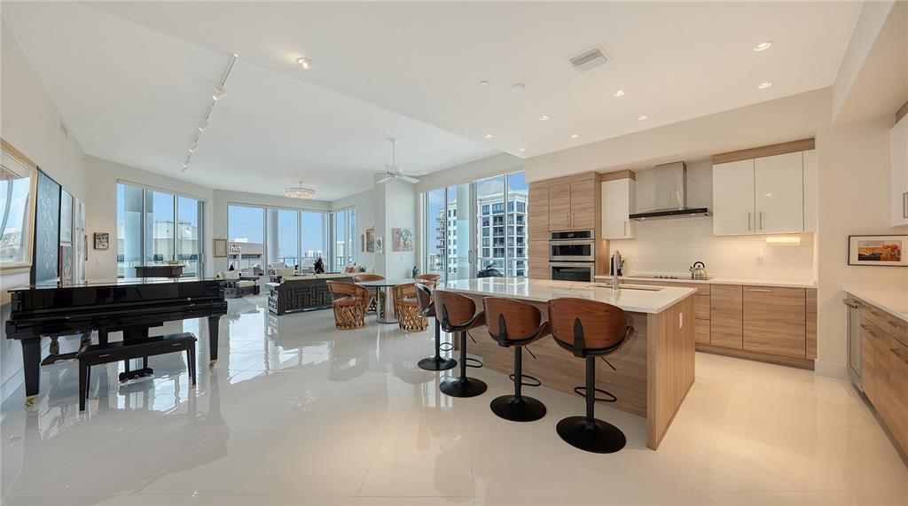 111 South Pineapple Avenue, Unit 1210 Sarasota, FL 34236 - Photo 35 of 54 a kitchen with stainless steel appliances granite countertop a stove a sink a dining table and chairs with wooden floor