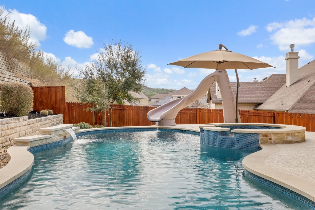 5812 Davenport Divide Road Austin, TX 78738 - Photo 35 of 40 A freeform pool designed for both relaxation and play, complete with integrated spa, waterfall feature, and a curved slide. The stone accents and tiered landscaping add visual depth, while open sky views make the space feel expansive.