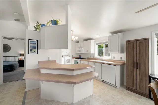 a large white kitchen with a sink and dishwasher a refrigerator with white cabinets