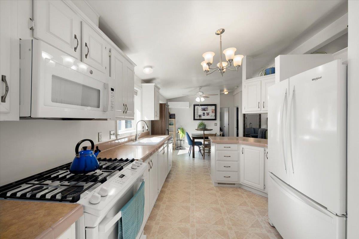 7155 Stewart Mine Road Placerville, CA 95667 - Photo 15 of 68 a kitchen with stainless steel appliances granite countertop a stove a refrigerator a oven a dining table and chairs with white cabinets