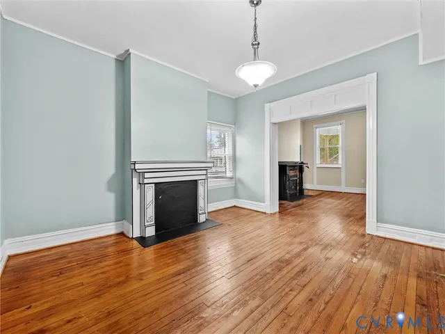 a view of an empty room with wooden floor fireplace and a window