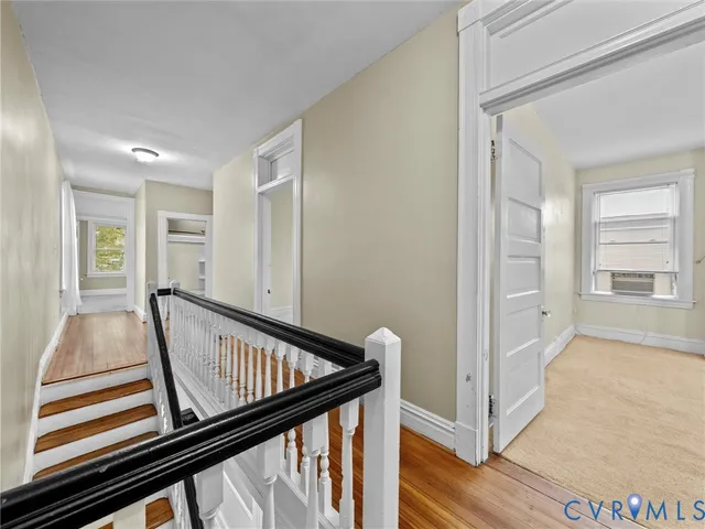 a view of a hallway with wooden floor and stairs