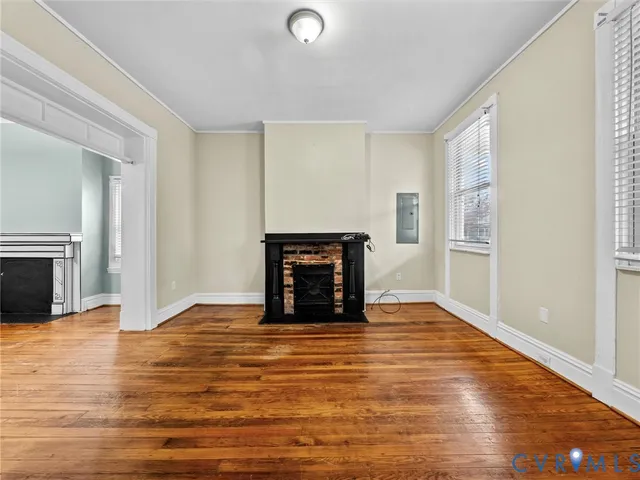 a view of an empty room with wooden floor fireplace and a window