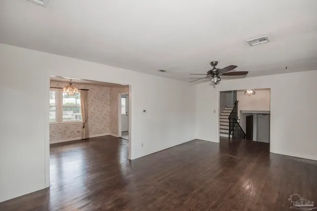 an empty room with wooden floor chandelier and windows