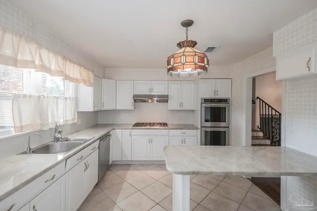 a kitchen with stainless steel appliances granite countertop a stove a sink and a window