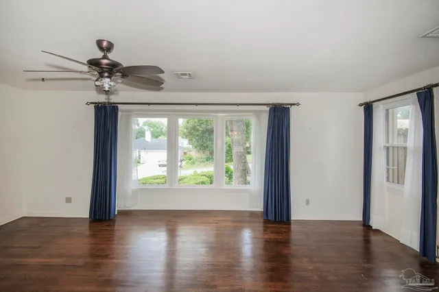 a view of an empty room with a window and wooden floor