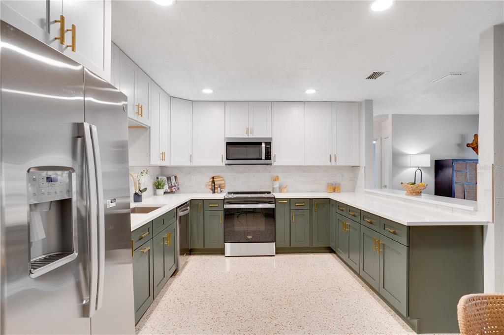 5135 101st Street North St. Petersburg, FL 33708 - Photo 12 of 46 a kitchen with stainless steel appliances granite countertop a refrigerator a stove top oven a sink and dishwasher