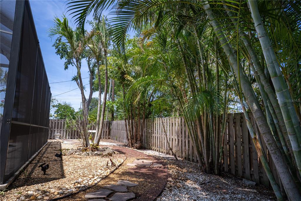 5135 101st Street North St. Petersburg, FL 33708 - Photo 37 of 46 a backyard of a house with table and chairs a barbeque and a large trees with wooden fence