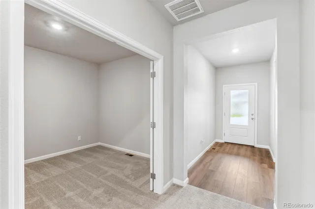 an empty room with wooden floor and windows