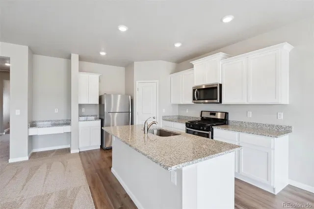 a kitchen with granite countertop a sink stainless steel appliances and white cabinets