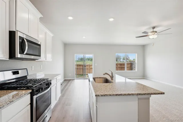 a kitchen with granite countertop stainless steel appliances a sink stove top oven and cabinets