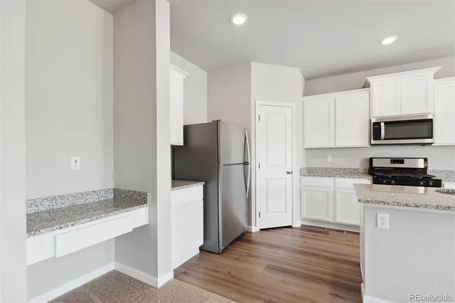 a kitchen with granite countertop a refrigerator stove and microwave