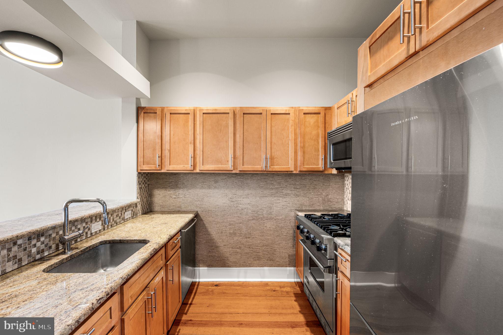 38 North Front Street, Unit 1F Philadelphia, PA 19106 - Photo 4 of 12 a kitchen with stainless steel appliances granite countertop a sink stove and refrigerator