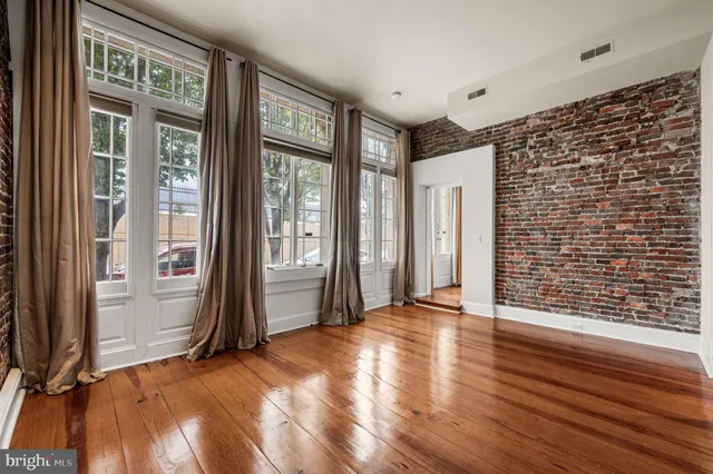a view of an empty room with glass door and wooden floor