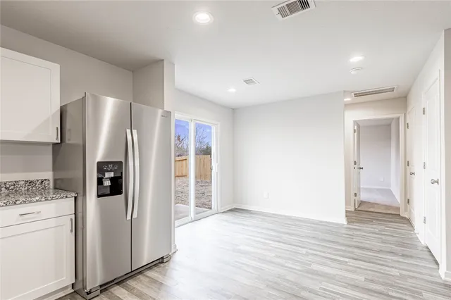 a view of a kitchen with refrigerator and wooden floor