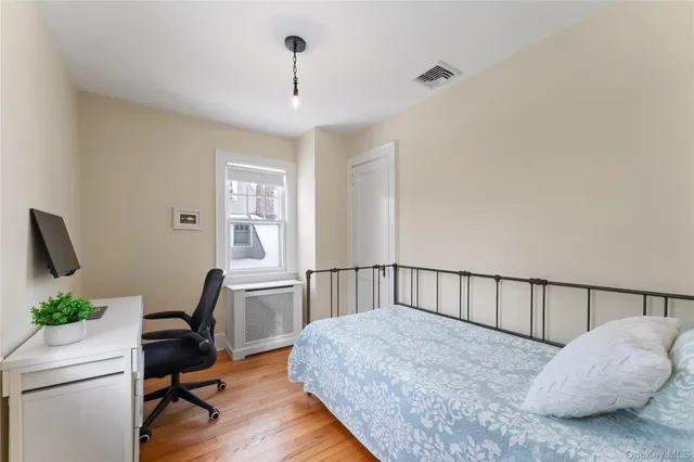 a bedroom with a bed a desk and chair with wooden floor