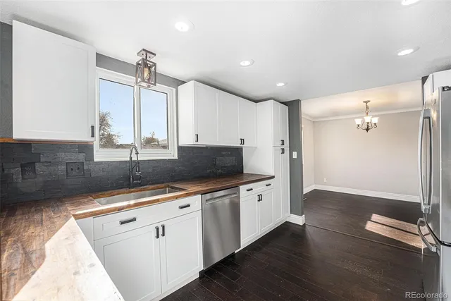 a large kitchen with stainless steel appliances a large counter top a sink and a refrigerator