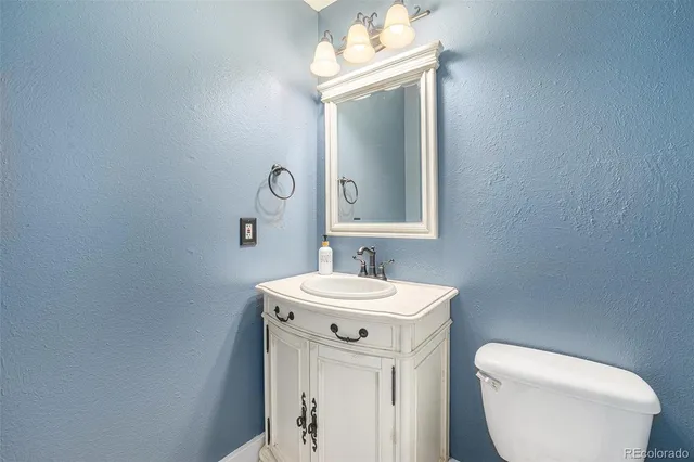 a bathroom with a toilet a sink a mirror and vanity