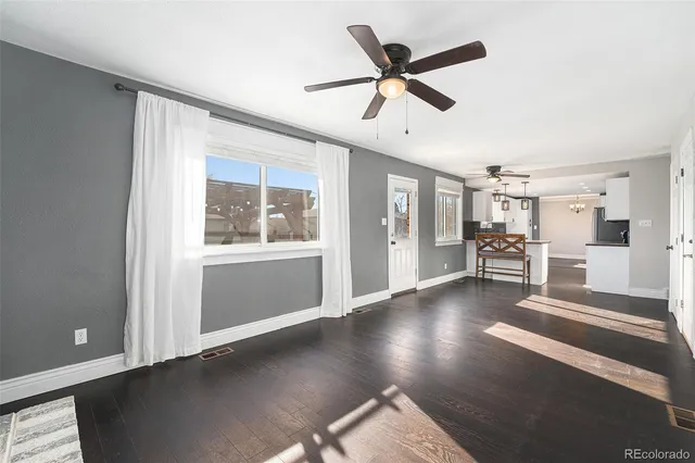 a view of a livingroom with wooden floor and a ceiling fan