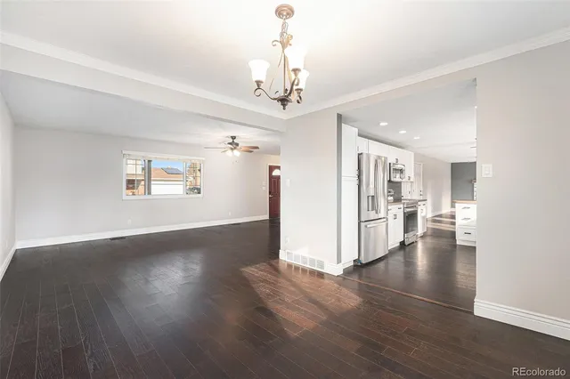a view of a livingroom with wooden floor a ceiling fan and windows