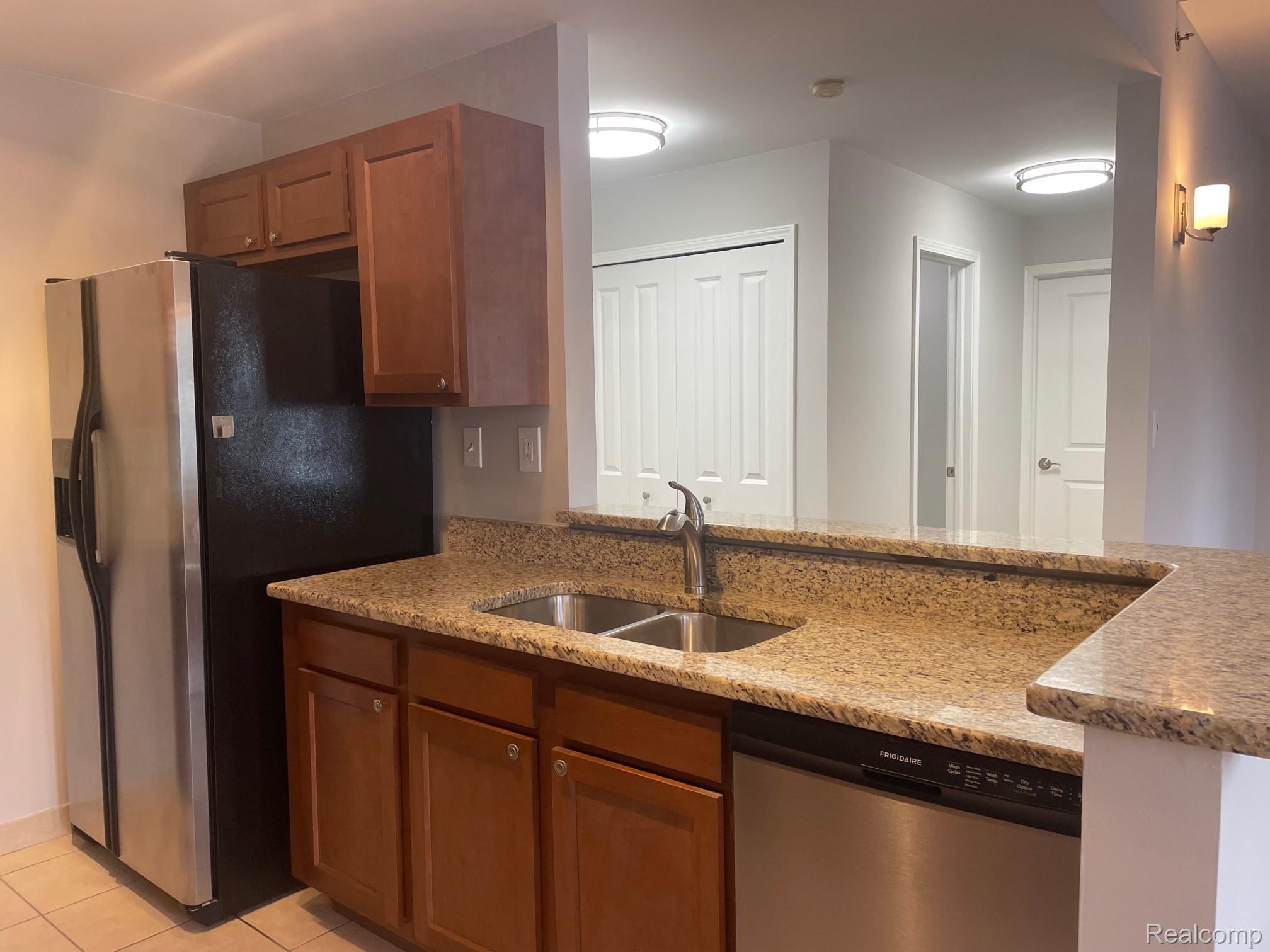 2727 East Maple Road Birmingham, MI 48009 - Photo 15 of 29 Kitchen featuring a stainless steel refrigerator, double basin sink, stone countertops, and wood-finish cabinetry
