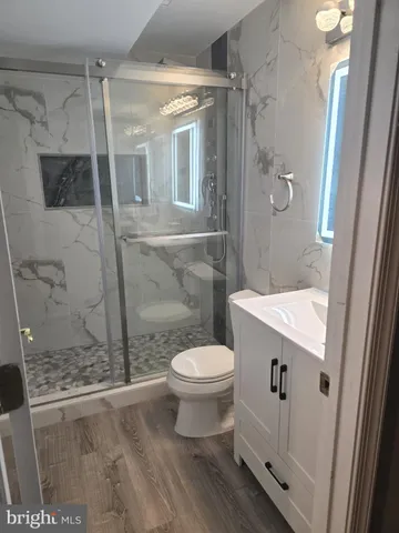 a bathroom with a granite countertop sink a toilet a mirror and shower