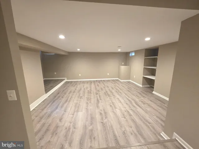 a view of empty room with wooden floor and kitchen