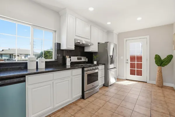 a kitchen with stainless steel appliances granite countertop a stove a sink and a refrigerator