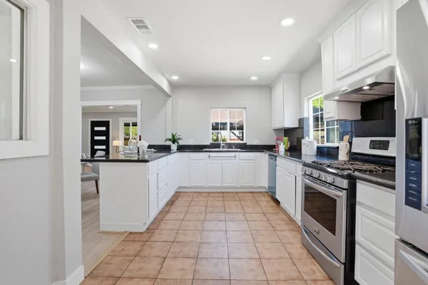 a large kitchen with stainless steel appliances granite countertop a stove top oven a sink and a refrigerator