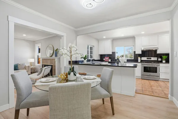 a living room with stainless steel appliances kitchen island granite countertop a dining table chairs and a refrigerator